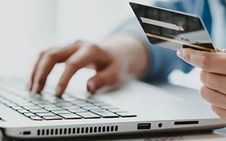 person with credit card typing on keyboard